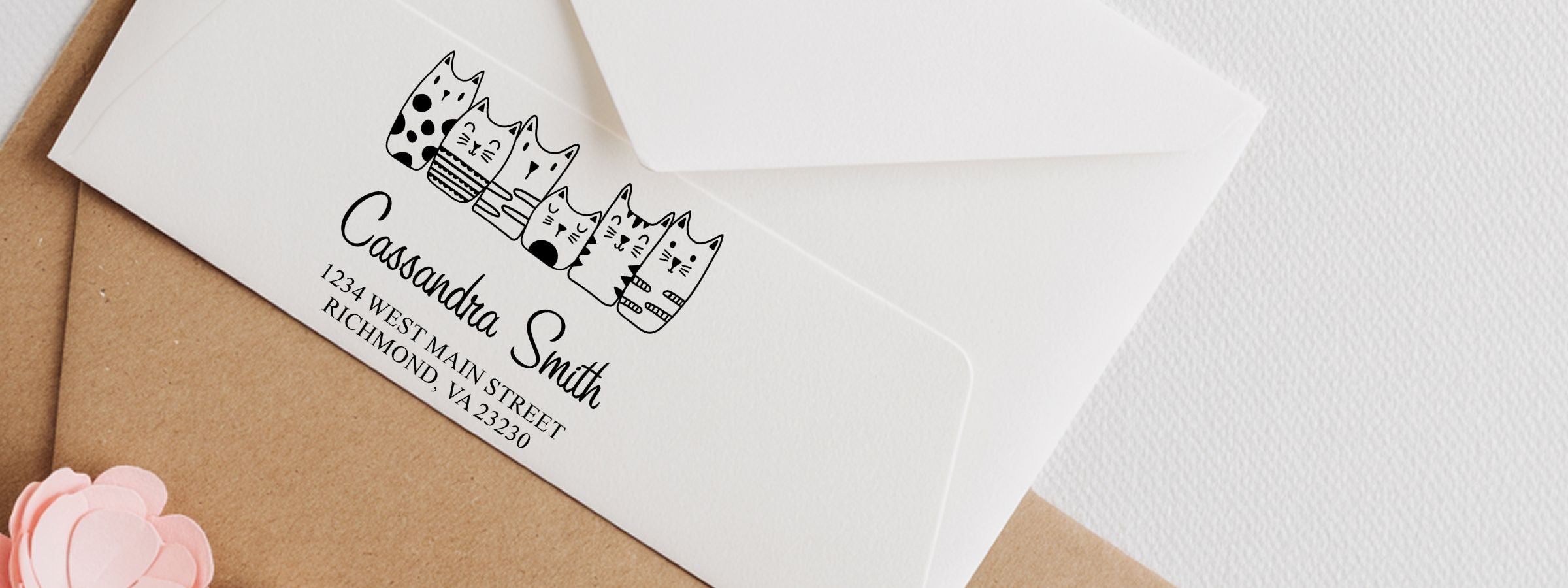 White envelope with black cat-themed address design reading “Cassandra Smith” on brown surface, for Cartoon Animals Designer Stamps.