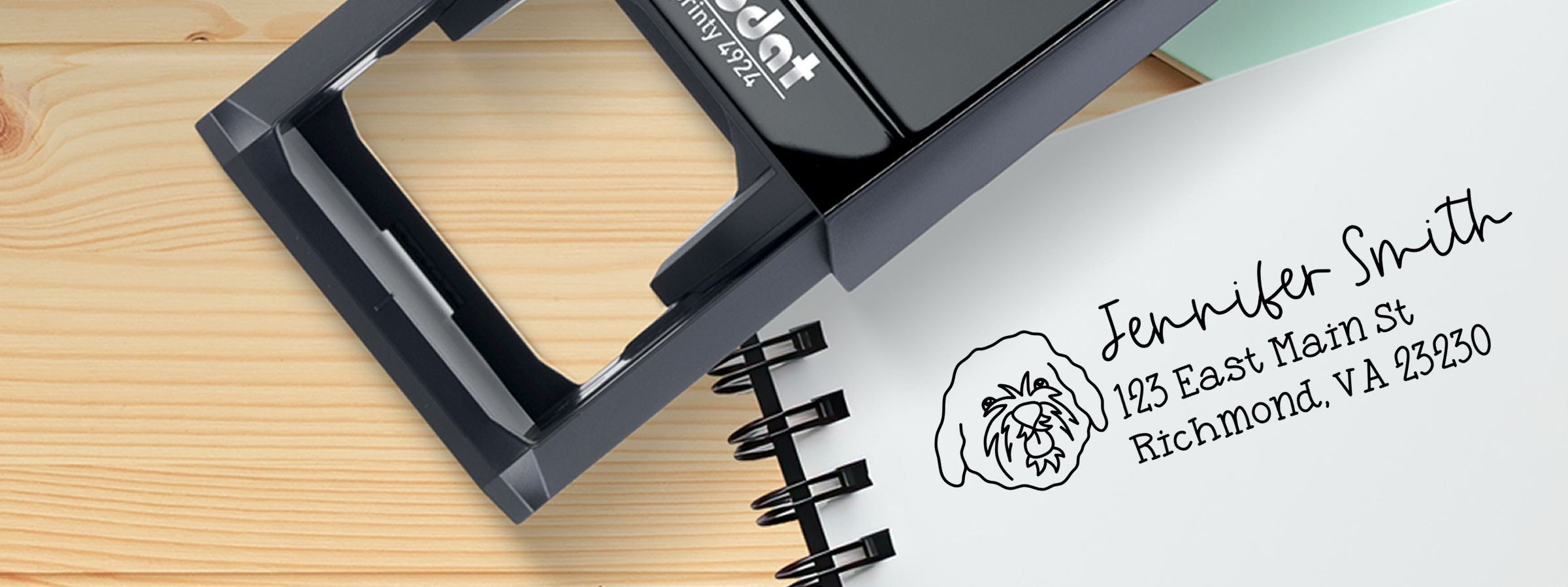 Black address stamp beside notebook page with dog logo and address, Cavapoo Dog Stamps and Custom Seals.