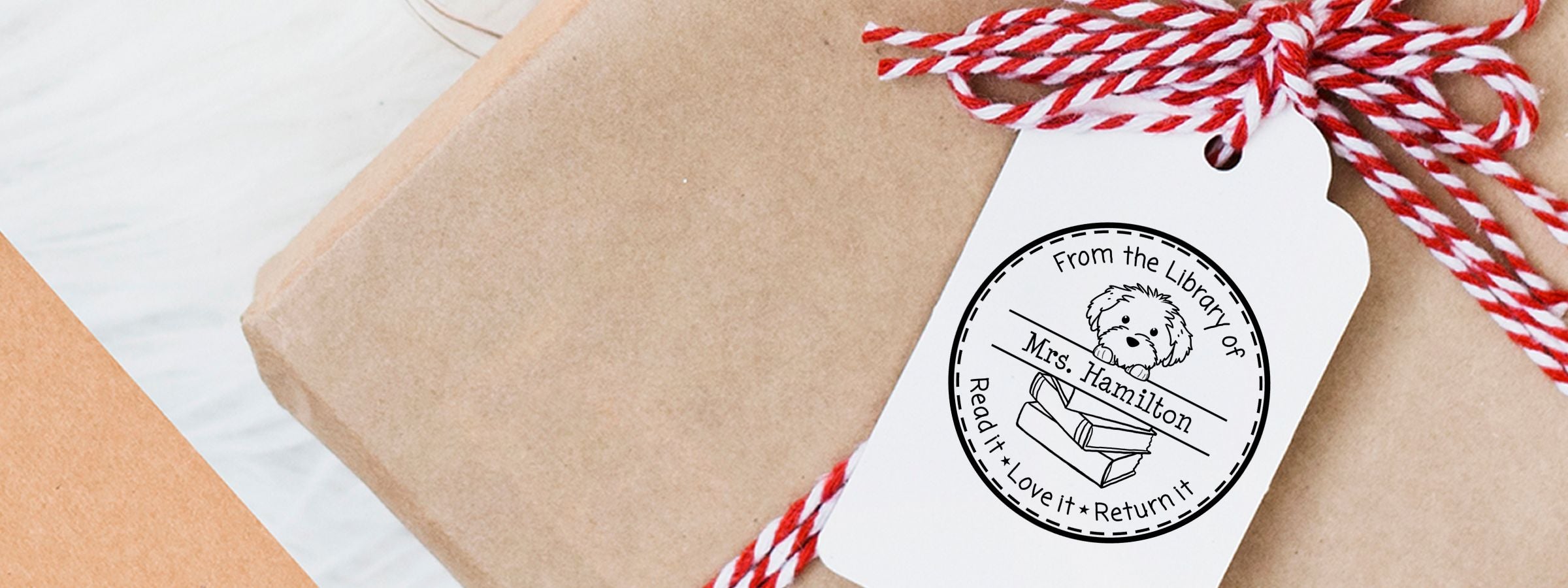 Brown gift box tied with red-and-white string, library return tag, and Cotton De Tulear Dog Stamps and Custom Seals dog-and-books art.