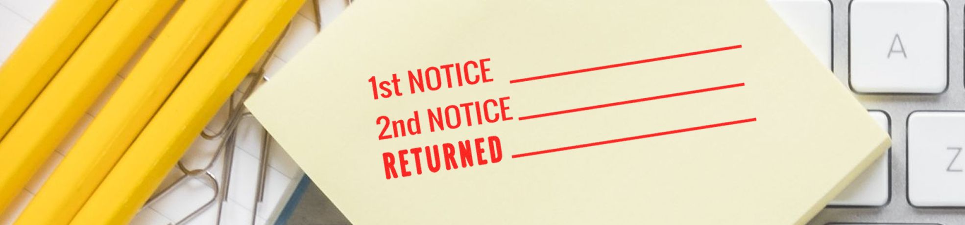 Stock Stamps sticky note on a keyboard labeled 1st Notice, 2nd Notice, and Returned beside yellow pens and paper clips.
