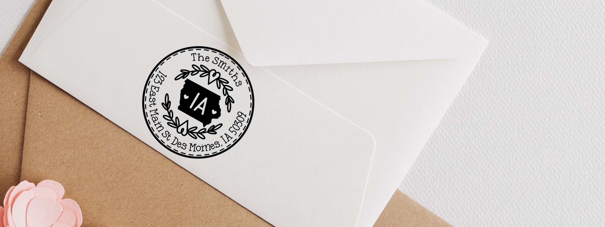 White envelopes on brown paper sealed with a black-and-white The Smiths sticker, with a pink paper flower; Iowa Designer Stamps and Seals.