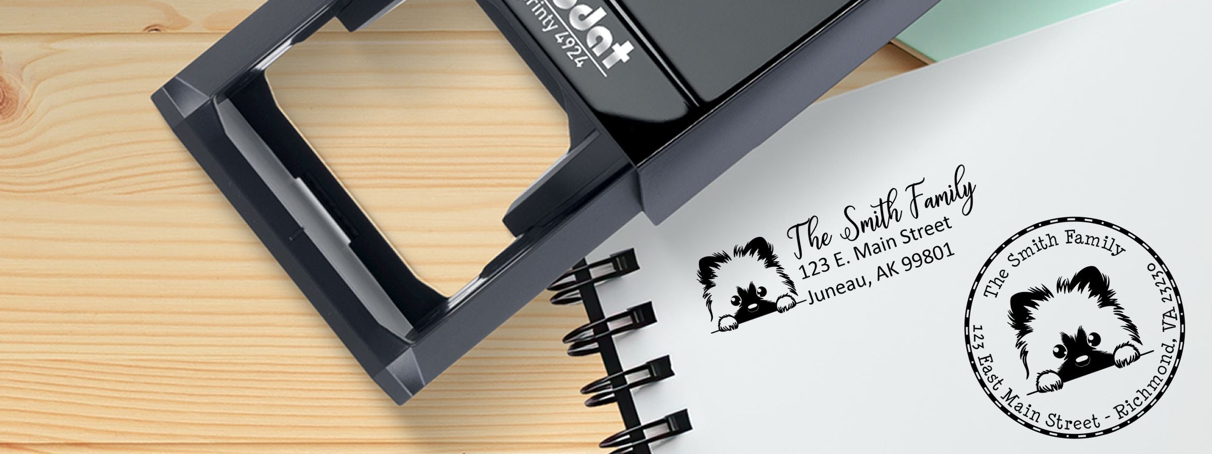 Black self-inking address stamp showing The Smith Family return address and dog illustration, with Keeshond Dog Stamps and Custom Seals on a desk.