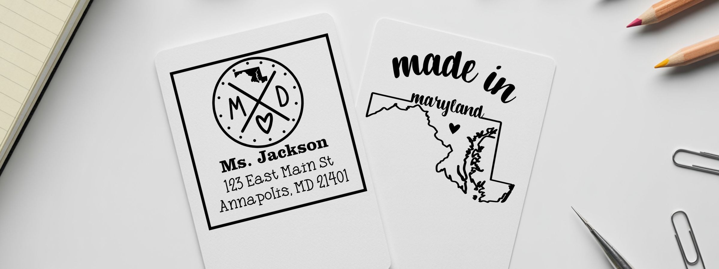Maryland Designer Stamps and Seals cards on a desk: one personalized “Ms. Jackson” card and one “made in maryland” state outline card.