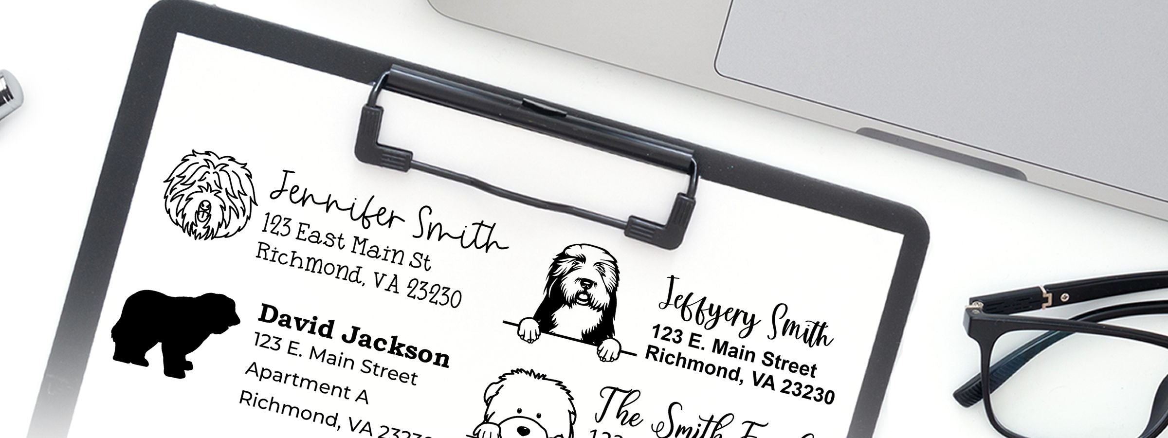 Clipboard of pet address labels with dog art, Old English Sheepdog Dog Stamps and Custom Seals, plus glasses and a laptop nearby.