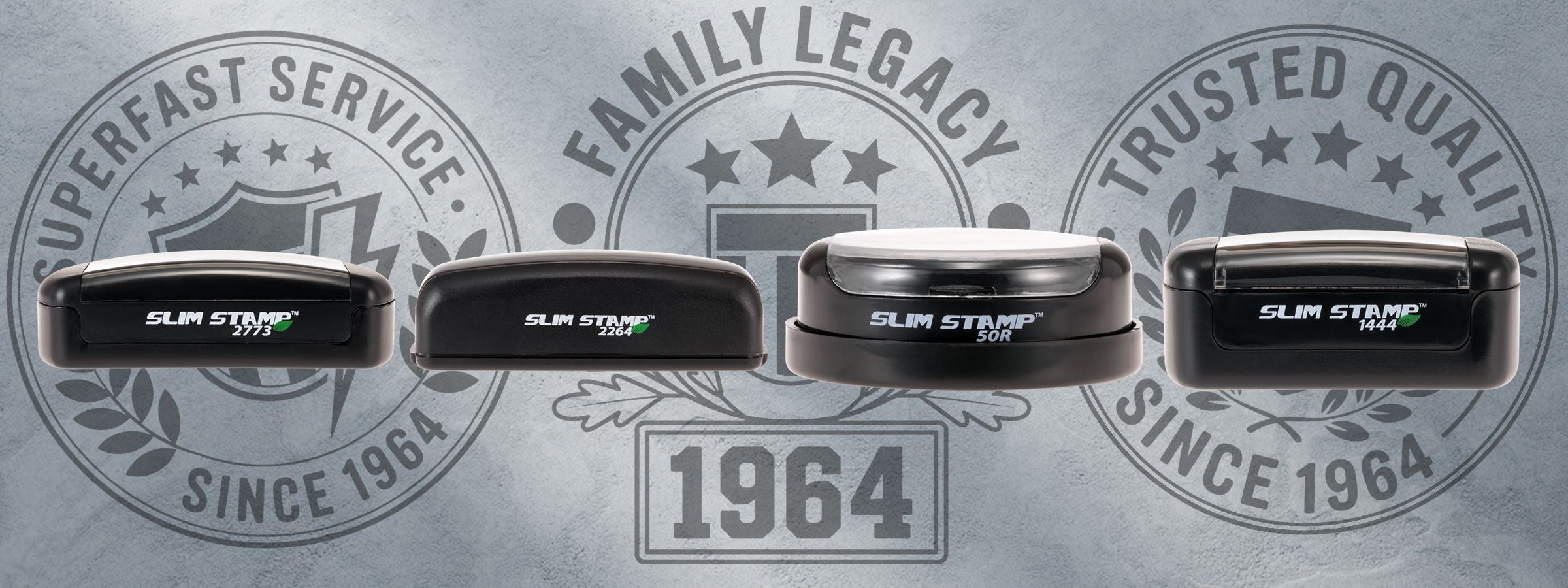 Four black Custom Slim Pre-Inked Stamps displayed in a row on a gray textured background with faded circular emblems and 1964.