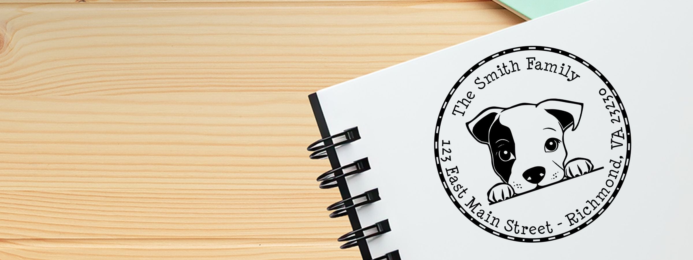 Spiral-bound notebook on a wooden table with a personalized dog logo, The Smith Family address, and Staffordshire Bull Terrier Dog Stamps and Custom Seals.