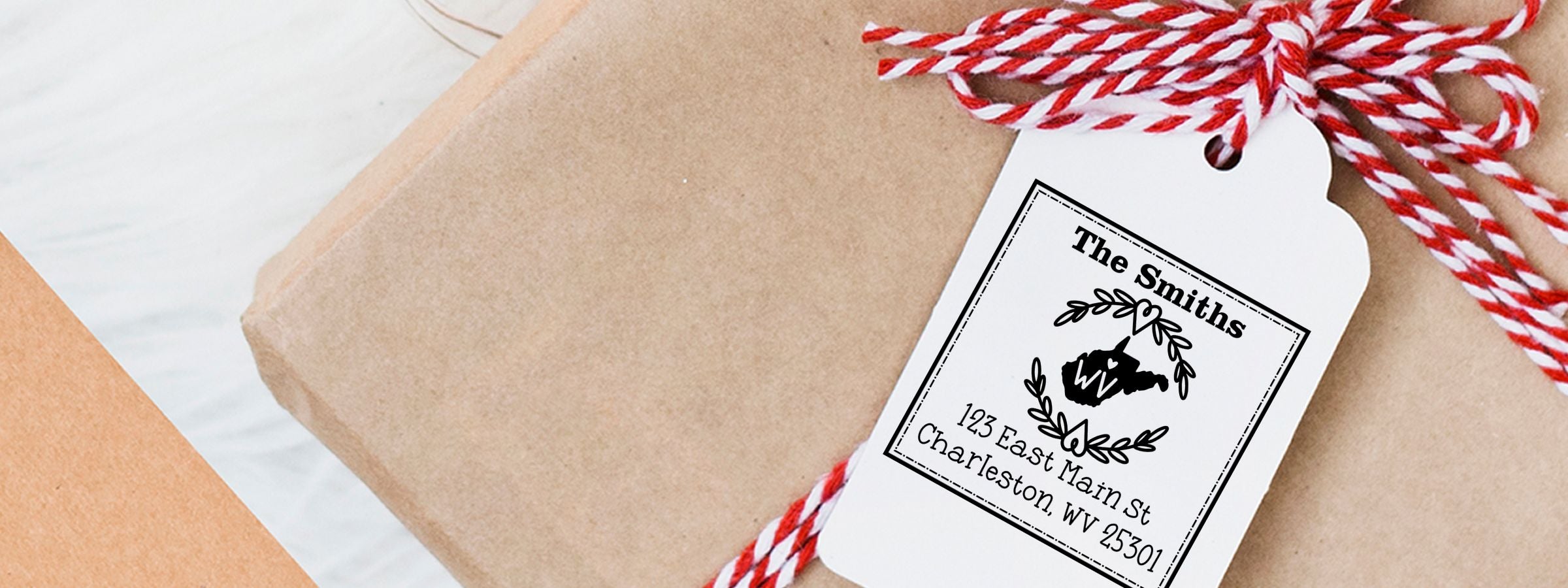 Wrapped gift with personalized tag for The Smiths, tied in red-and-white twine, by West Virginia Designer Stamps and Seals.