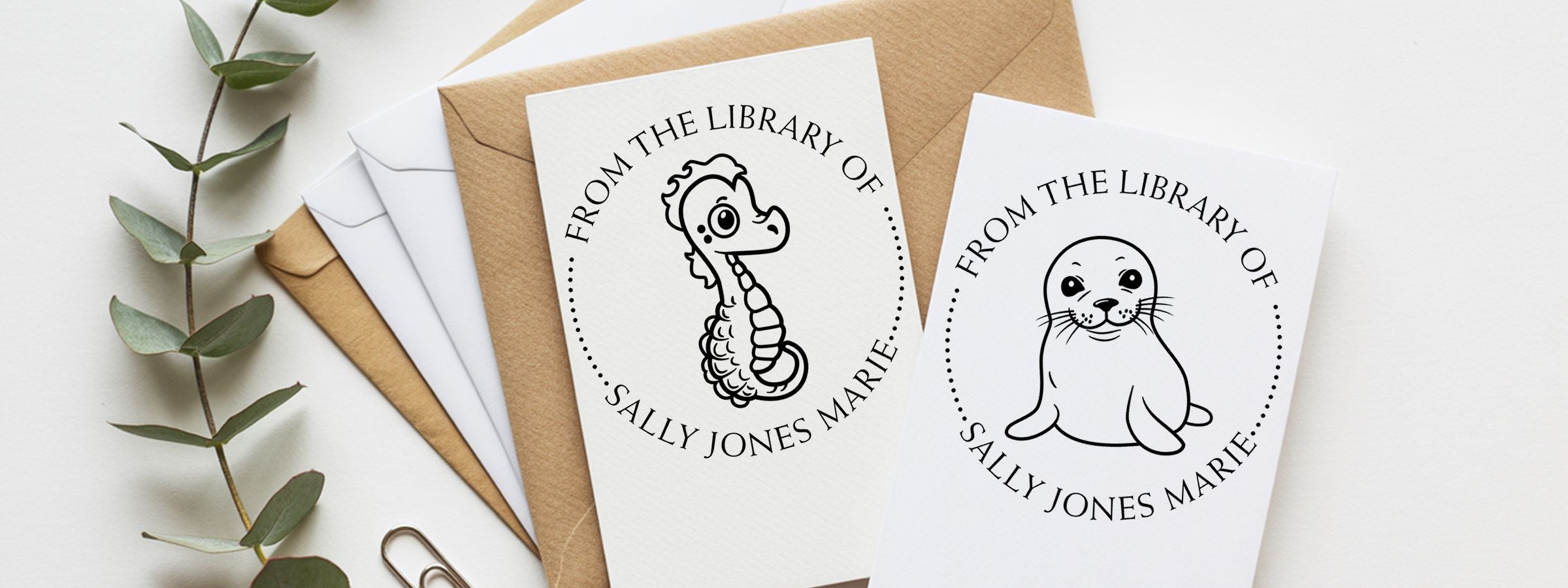 Kraft and white envelopes with personalized library cards, seahorse and seal art, eucalyptus, and Wildlife and Exotic Designer Stamps.