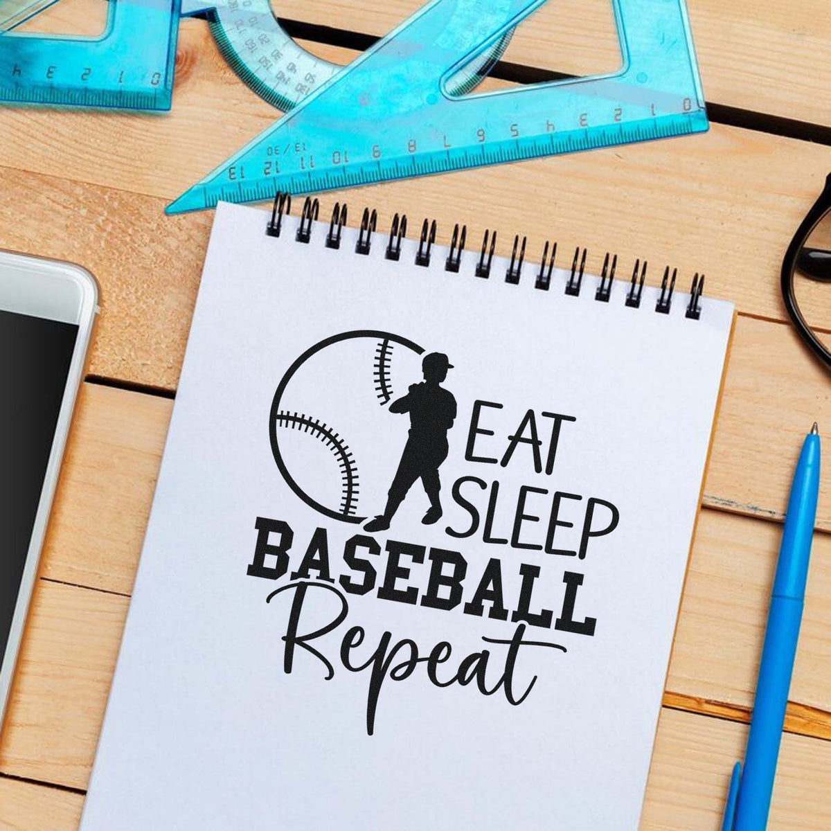 Baseball-themed custom rubber stamp design with Eat Sleep Baseball Repeat on a notebook.