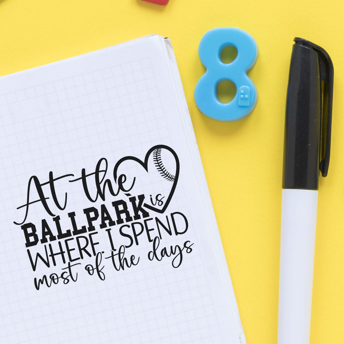 At The Ballpark Baseball Heart Pre-Inked Stamp – Slim imprint stamped in black ink. Mixed lettering reads "At the ballpark is where I spend most of the days," with a baseball heart.