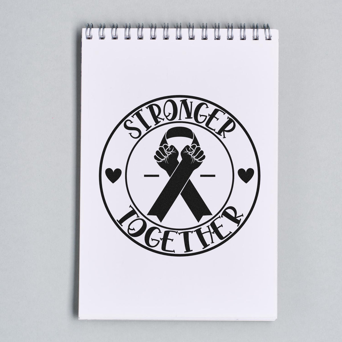 Stronger Together Ribbon Badge Premium Wood-Mounted Stamp - Vintage Pro imprint stamped in black ink. A circular "Stronger together" badge surrounds an awareness ribbon topped with two raised fists.