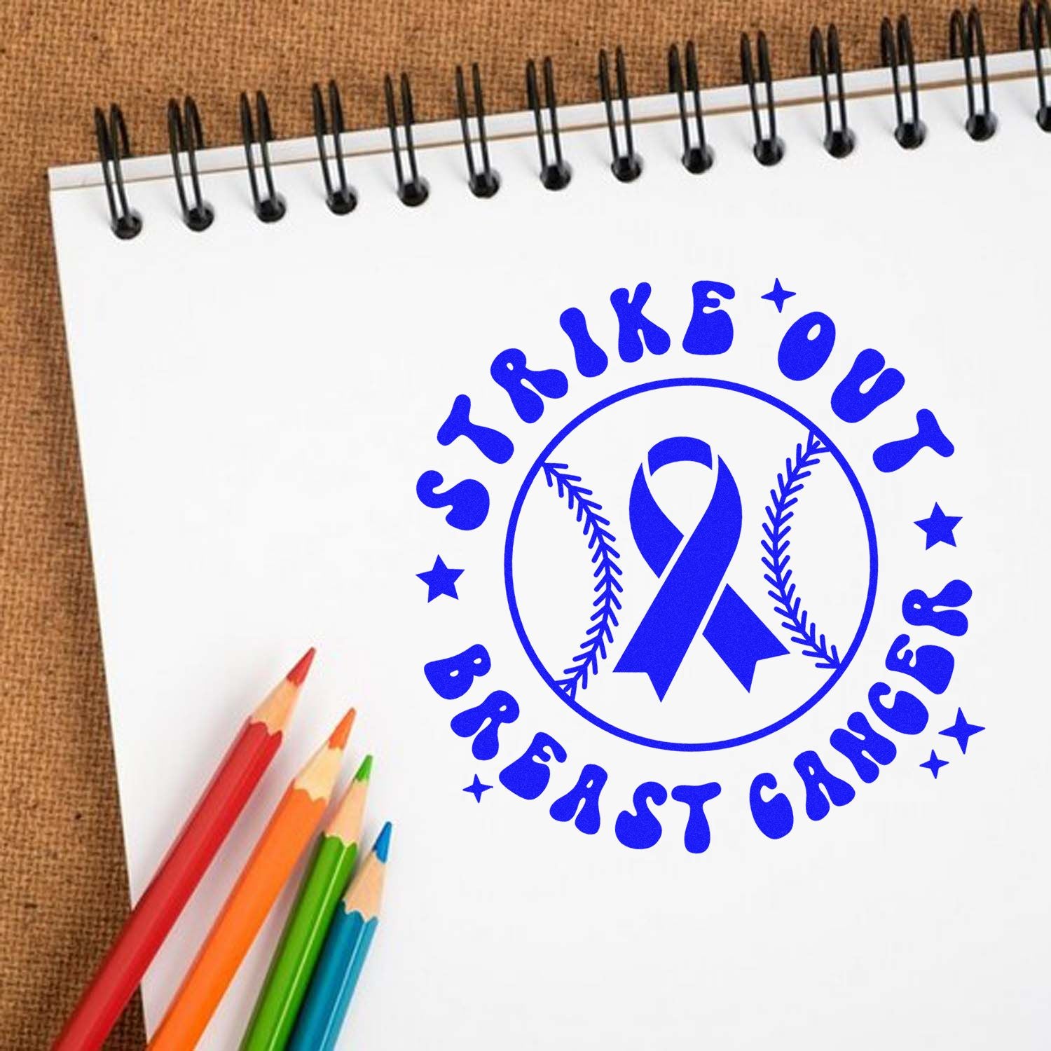 Strike Out Breast Cancer rubber stamp design with awareness ribbon logo on notebook, ideal for fundraising and event branding.