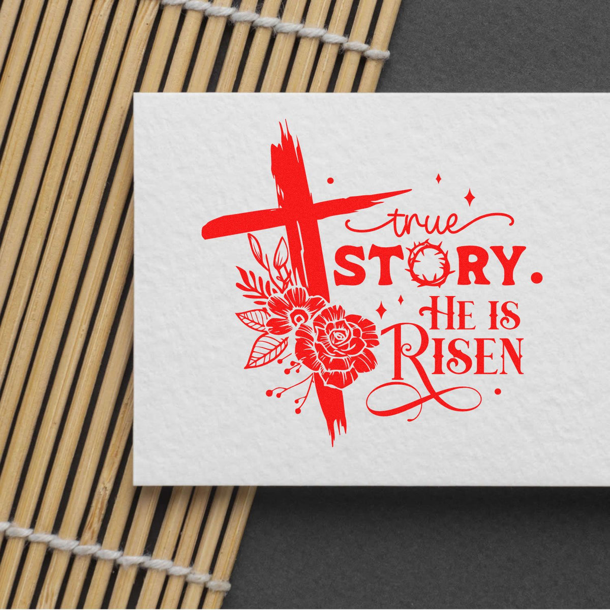 Easter rubber stamp design with red cross, flowers, and True Story. He Is Risen Christian greeting on white paper.