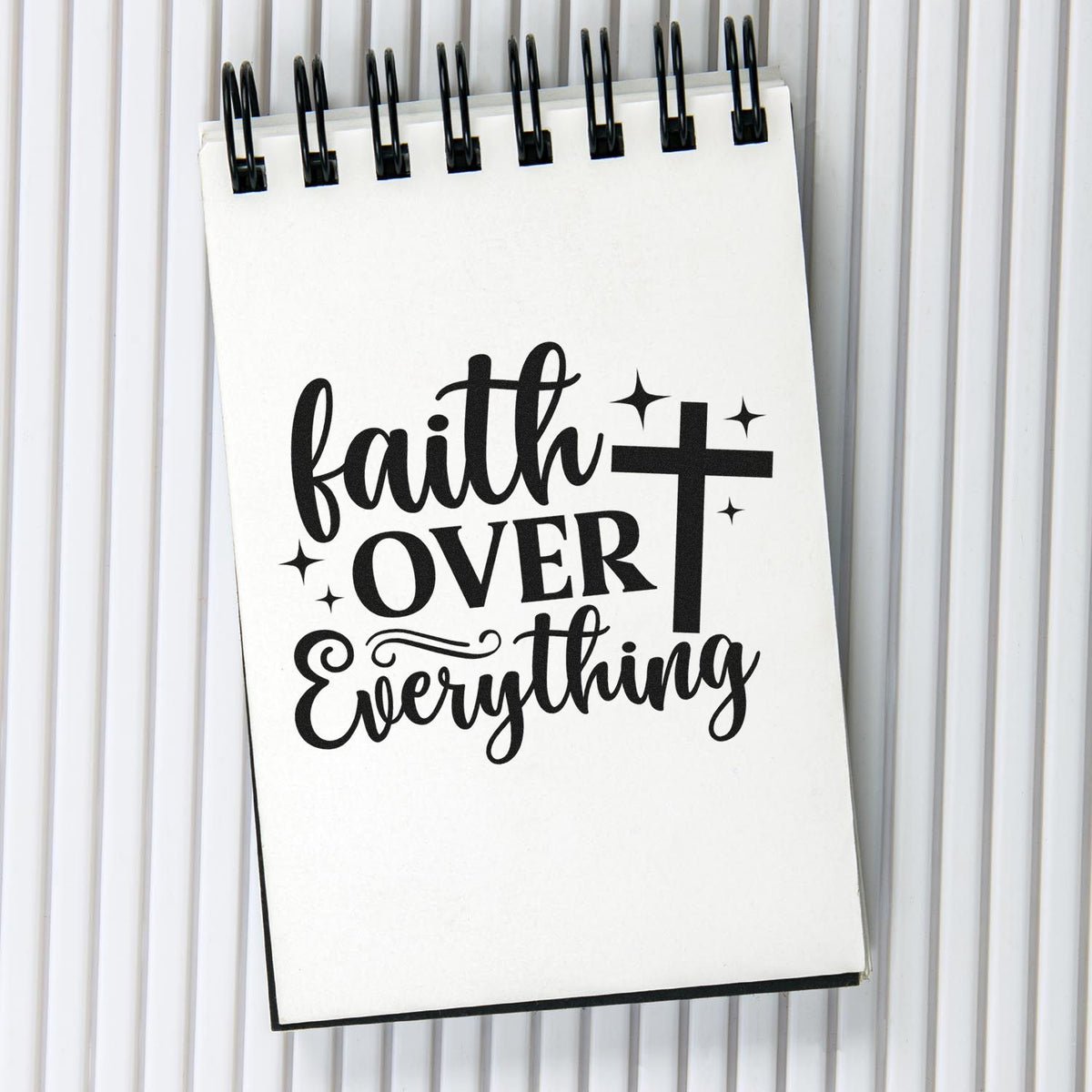 Faith over everything Christian rubber stamp design with cross and stars on a spiral notebook