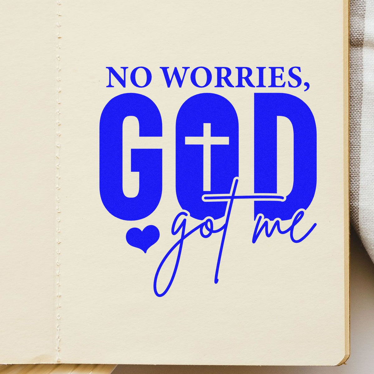 Christian rubber stamp design reading No Worries, God Got Me in bold blue on paper.