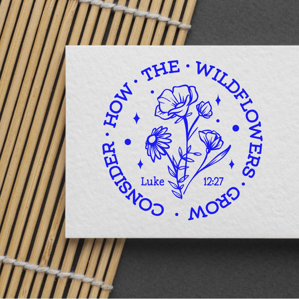 Custom floral rubber stamp with Luke 12:27 verse, Consider how the wildflowers grow, in blue on paper.