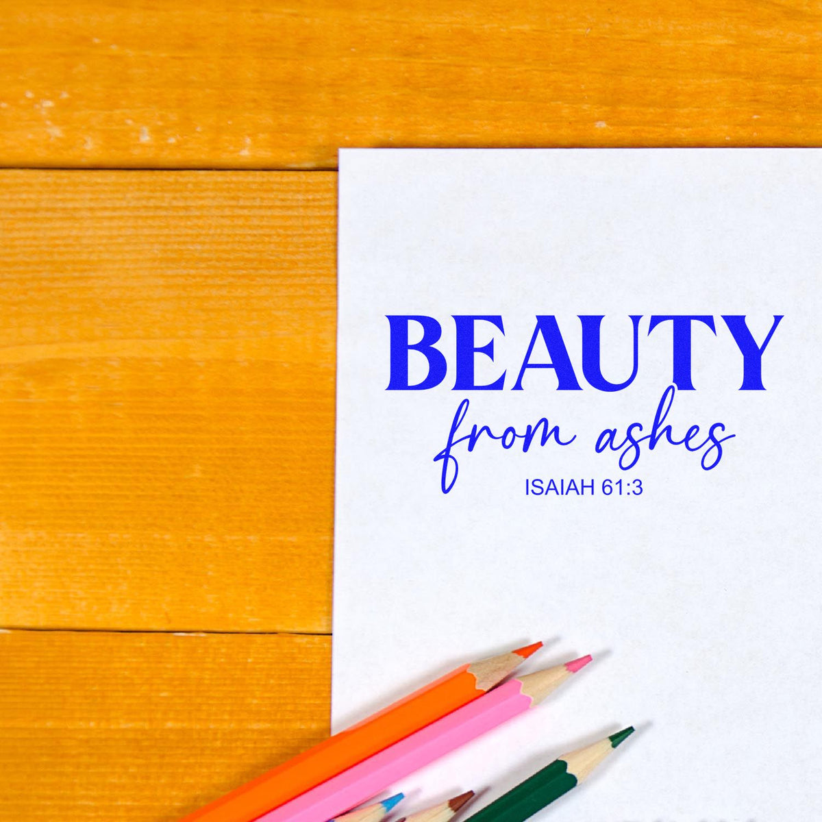 Bible verse rubber stamp design reading Beauty from Ashes, Isaiah 61:3, on white paper with colored pencils.
