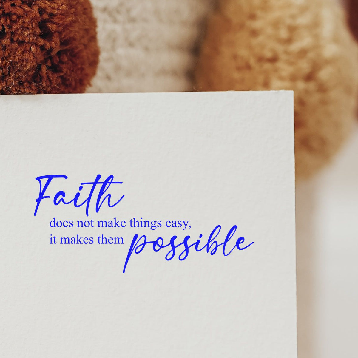 Blue inspirational faith rubber stamp quote on white paper: Faith does not make things easy, it makes them possible.
