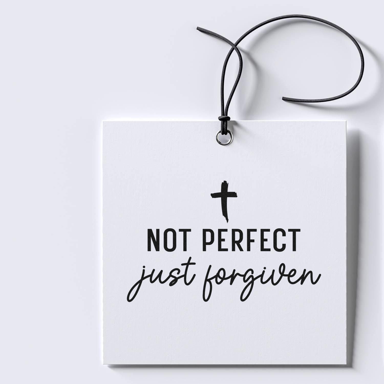 Christian rubber stamp design reading Not perfect, just forgiven with cross on a gift tag mockup.