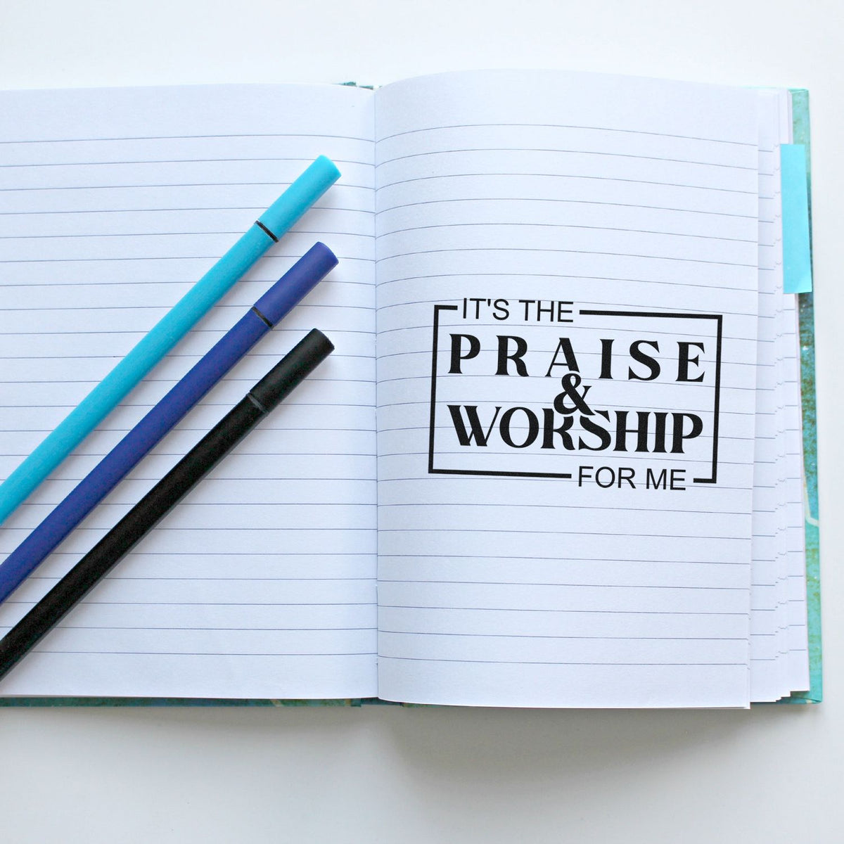 Christian praise and worship rubber stamp design in an open lined notebook with pens, ideal for journaling, Bible study, or planners.