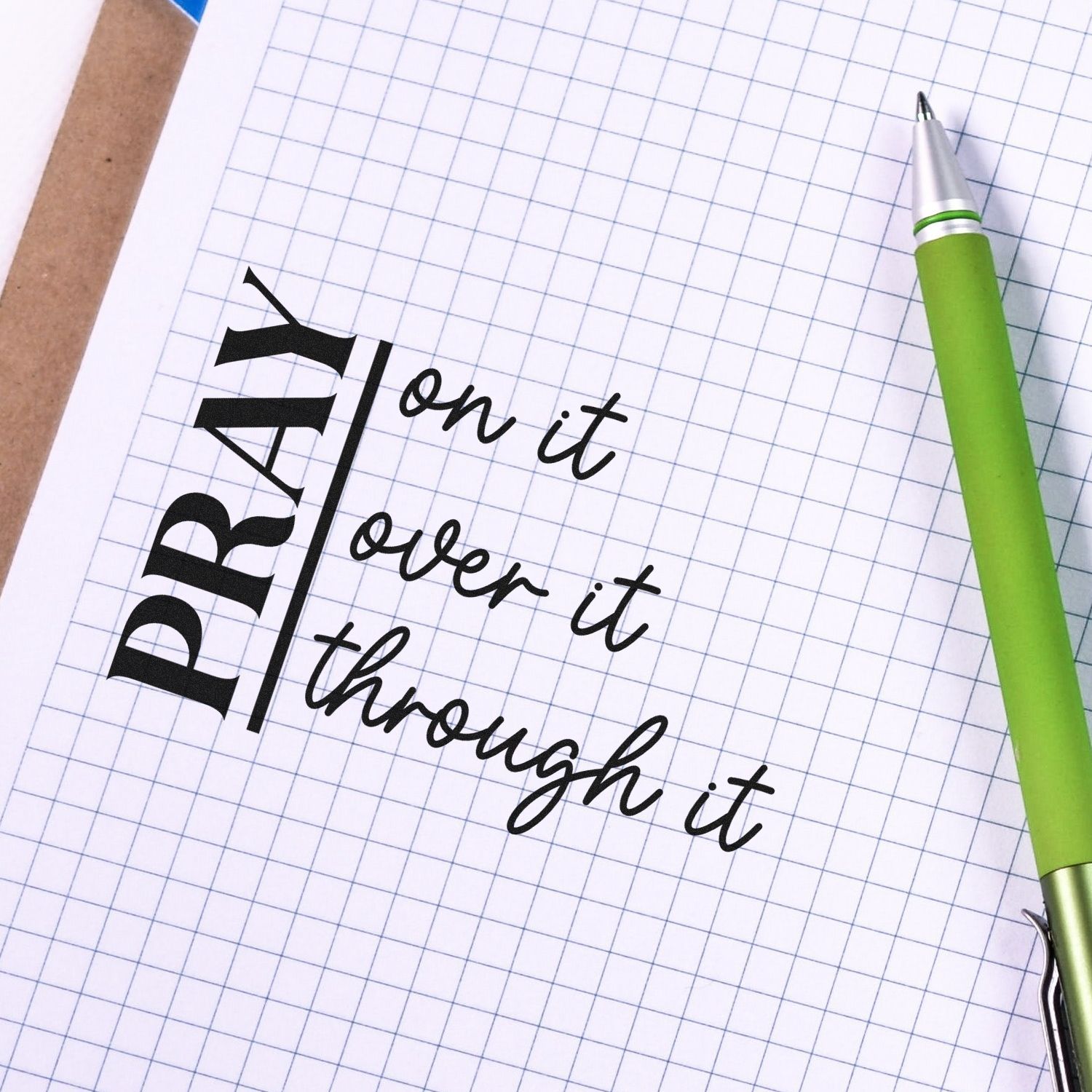 Custom rubber stamp quote Pray on it, over it, through it on graph paper, with green pen.