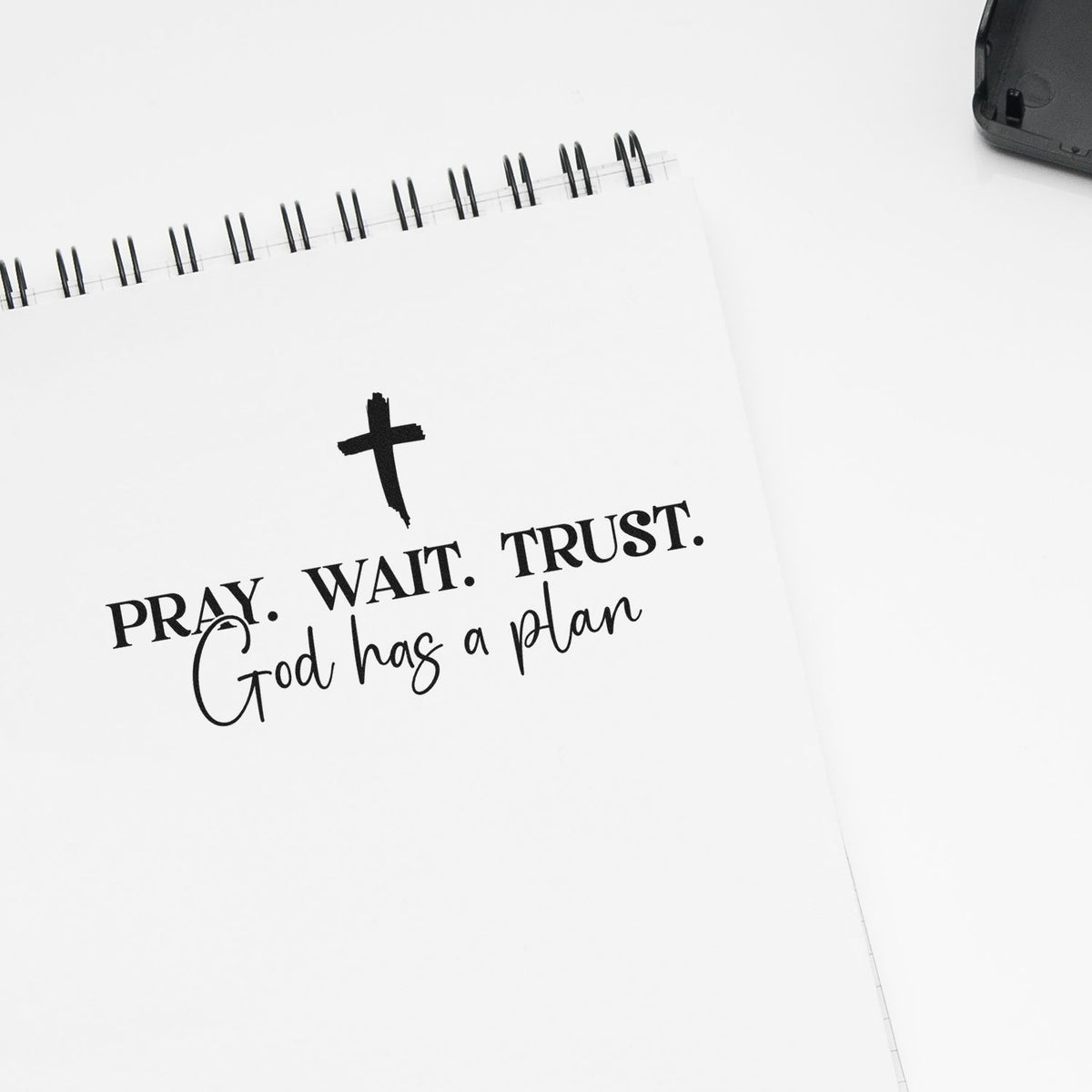 Faith-based rubber stamp design with cross and Pray. Wait. Trust. God has a plan on a notebook page.