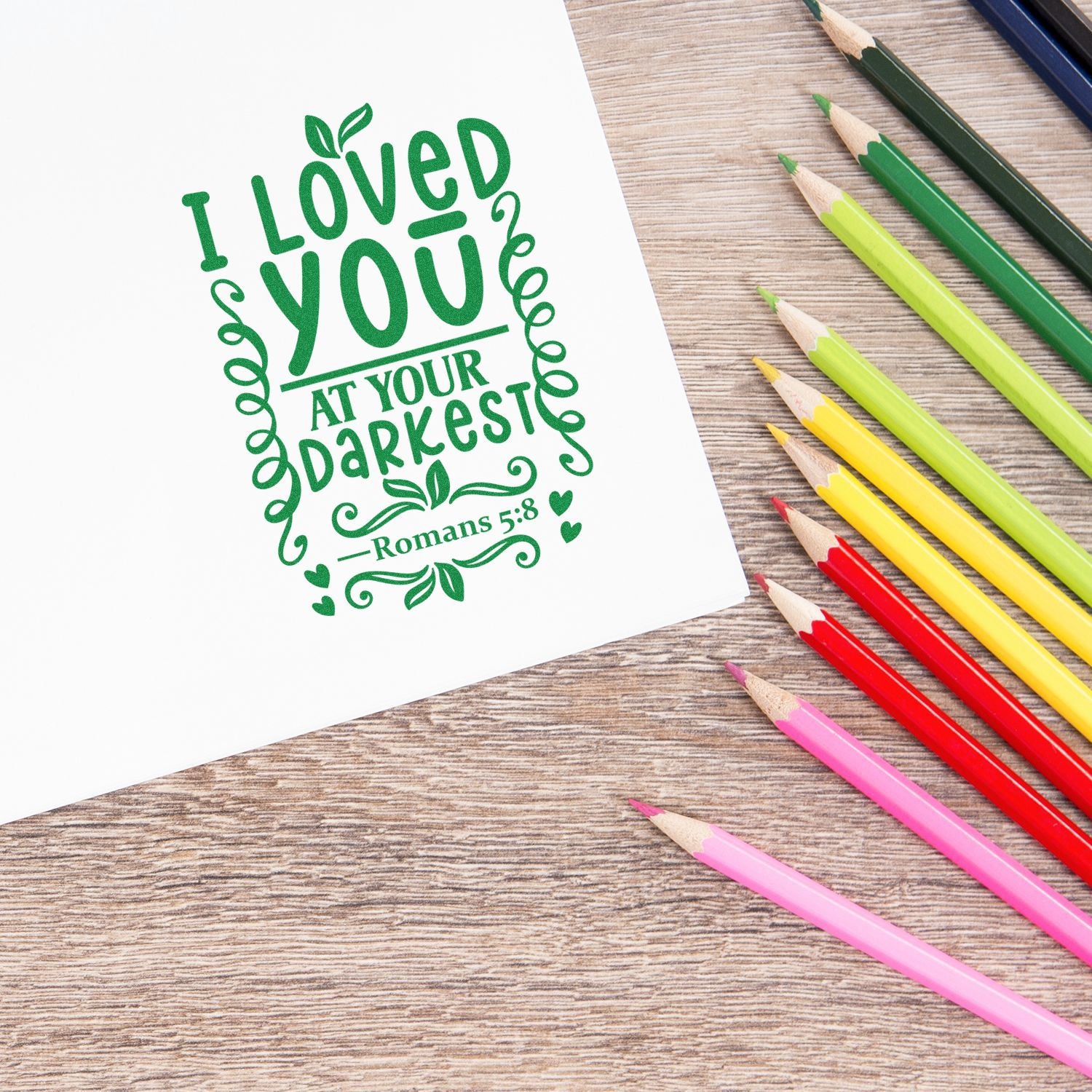 Bible verse rubber stamp design featuring Romans 5:8, I loved you at your darkest, in green lettering.