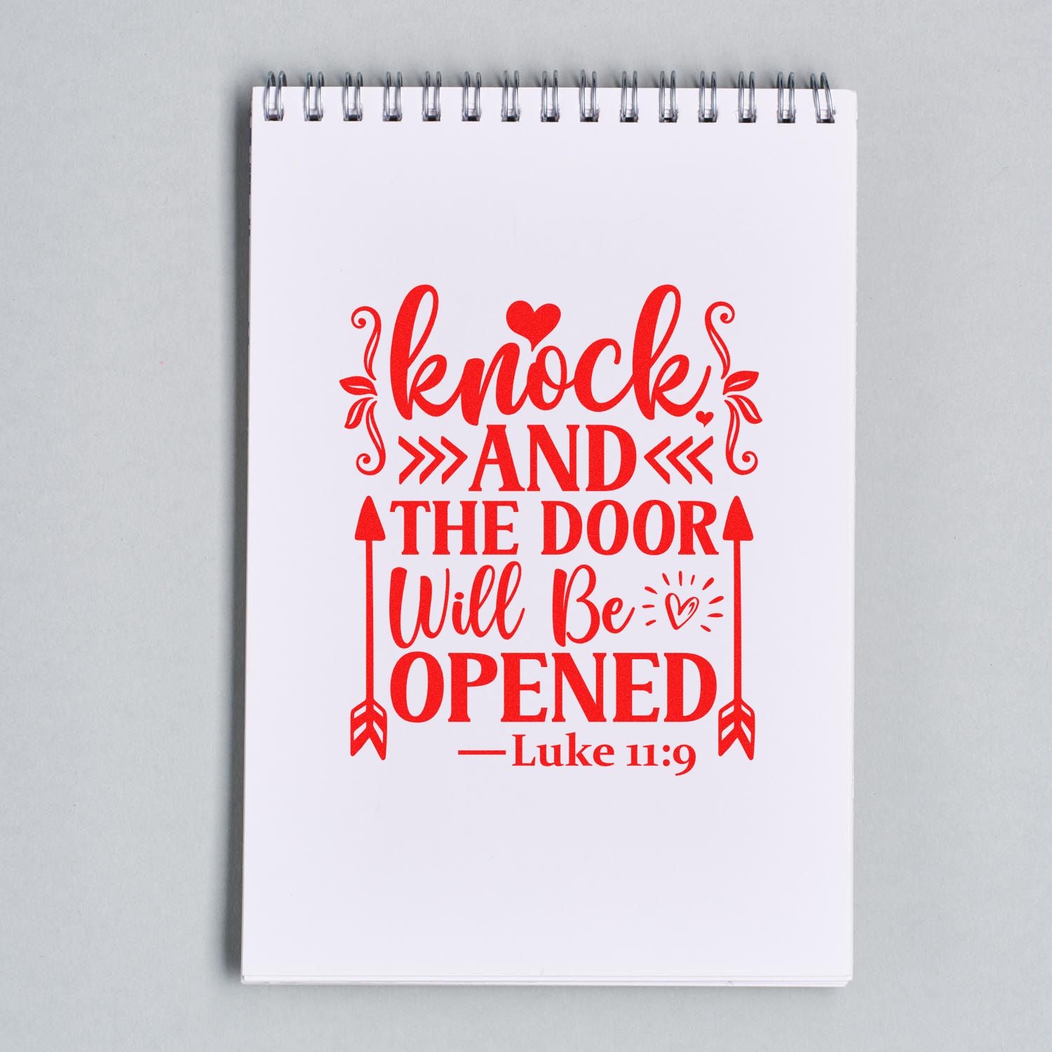 Christian rubber stamp design in red with Bible verse Knock and the door will be opened Luke 11:9 on notebook.