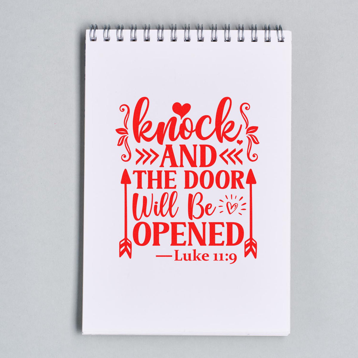 Bible verse rubber stamp design with Luke 11:9 quote, Knock and the door will be opened, in red on a notebook.