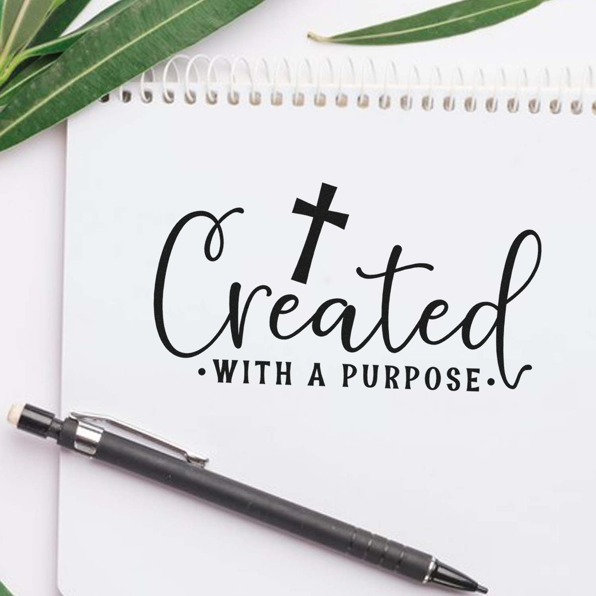 Inspirational rubber stamp mockup reading Created with a Purpose on a notebook with pen and leaves.