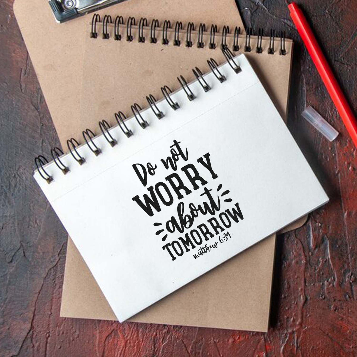 Bible verse rubber stamp design on spiral notebook reading Do not worry about tomorrow Matthew 6:34.