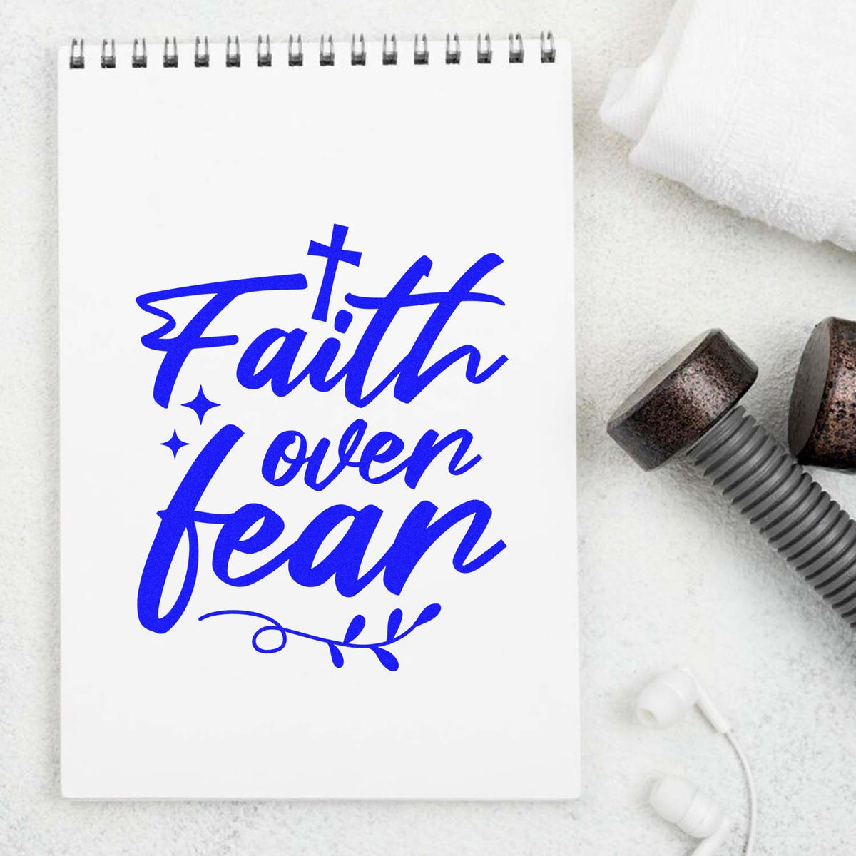 Faith Over Fear custom rubber stamp design with cross, stars, and leaf flourish on a notebook.