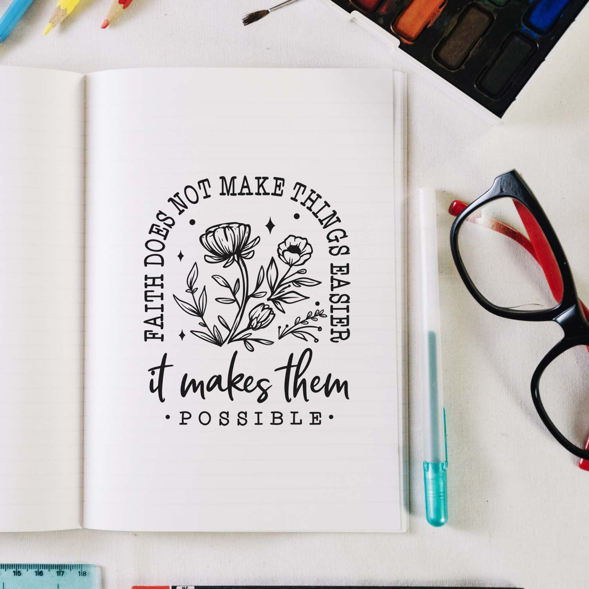 Floral faith quote rubber stamp on notebook, reading Faith does not make things easier, it makes them possible.