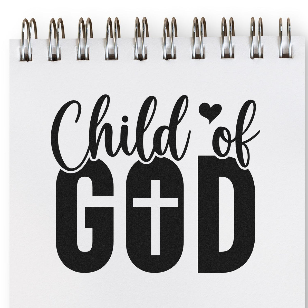 Child of God rubber stamp design with bold Christian typography and heart icon on a spiral notebook page.