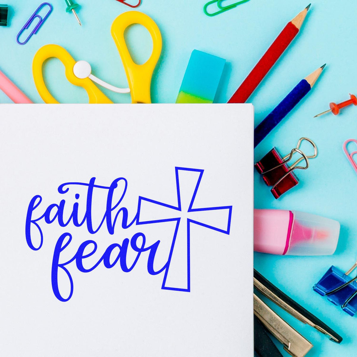 Faith and fear cross rubber stamp design on white paper surrounded by colorful stationery for Christian crafts.