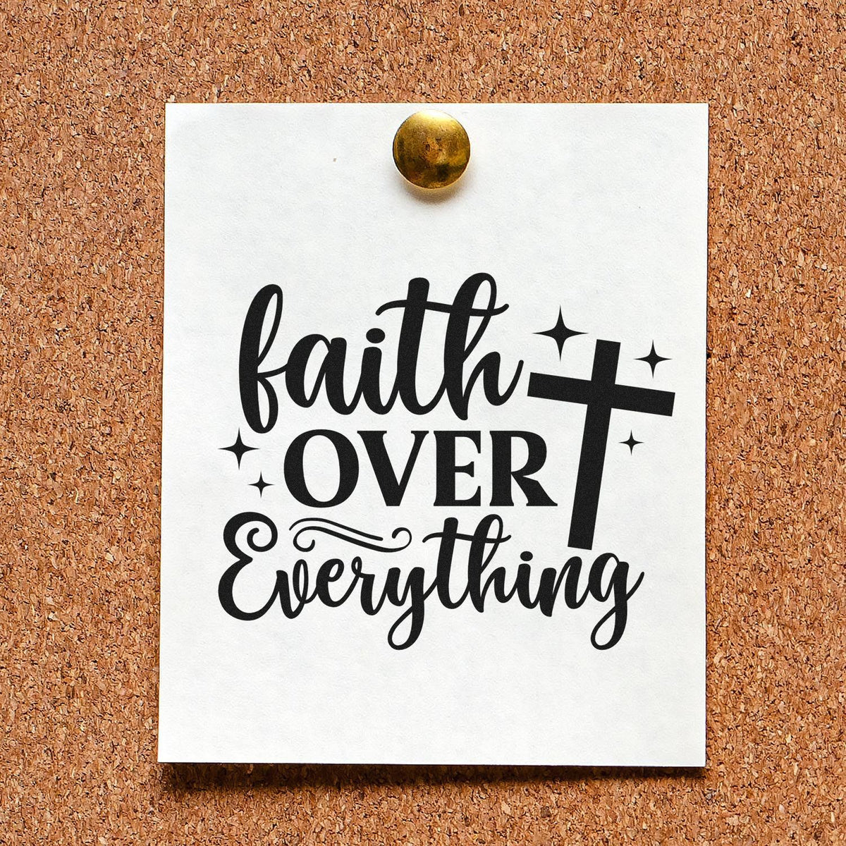 Christian faith over everything rubber stamp design with cross, displayed on pinned white paper on a corkboard.
