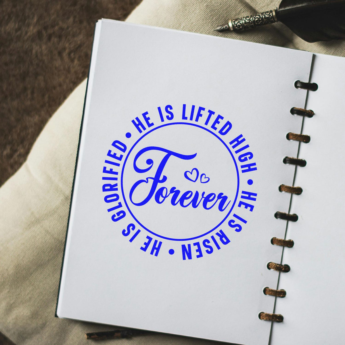 Christian Easter rubber stamp design with blue Forever He Is Risen, He Is Lifted High, Glorified text on notebook page.