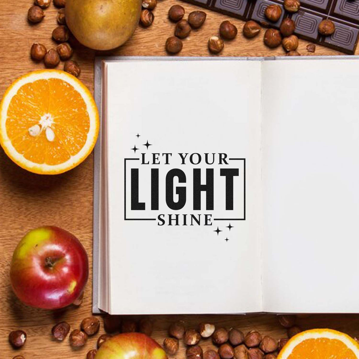 Inspirational rubber stamp design reading Let Your Light Shine on an open journal with fruit and coffee beans.