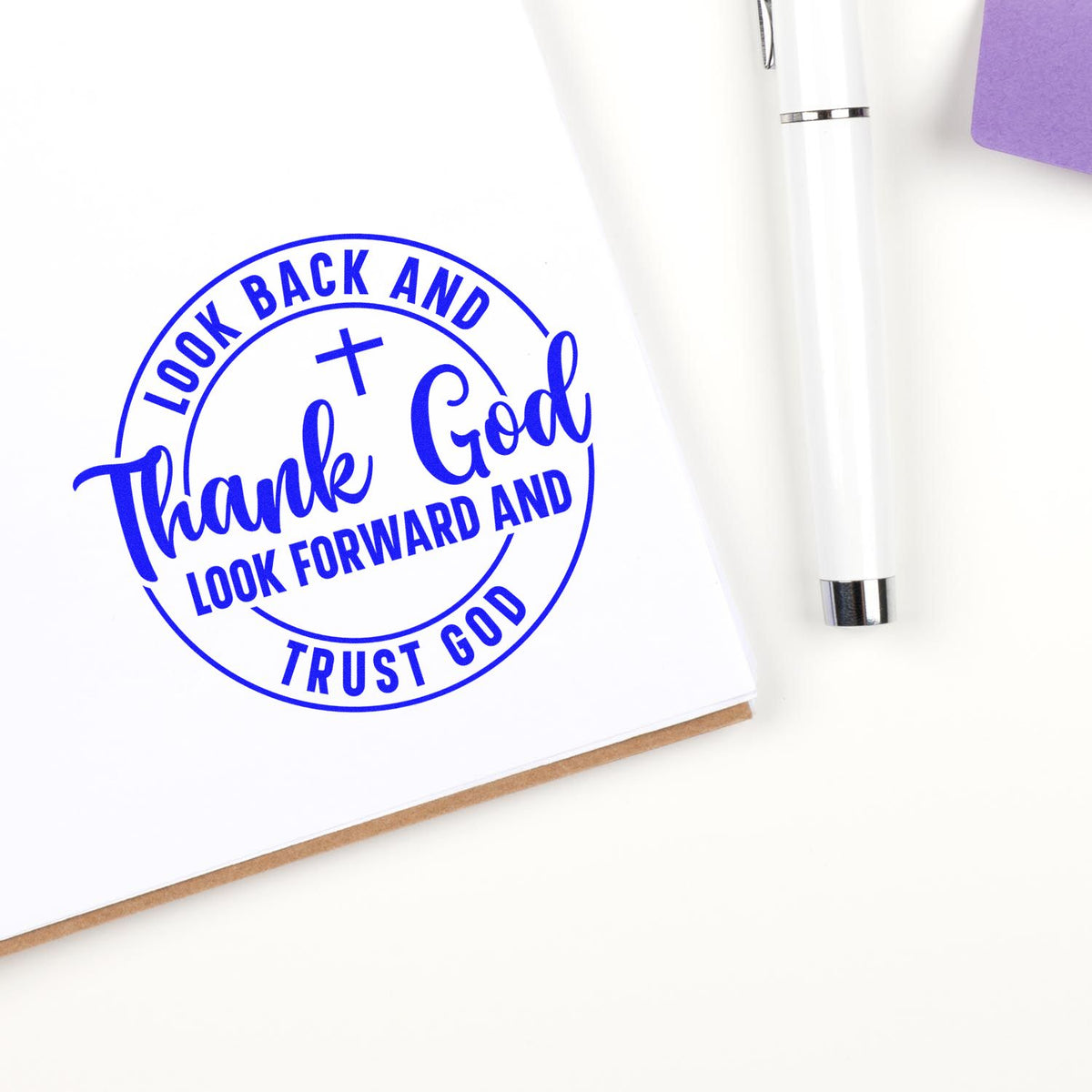 Faith-based rubber stamp reading Look back and thank God, look forward and trust God in blue on white paper.