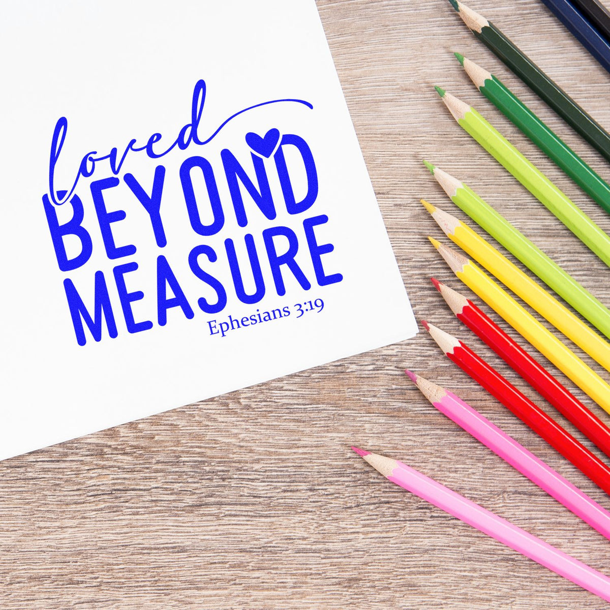 Loved Beyond Measure Ephesians 3:19 Christian rubber stamp design with colorful pencils on a wood desk.