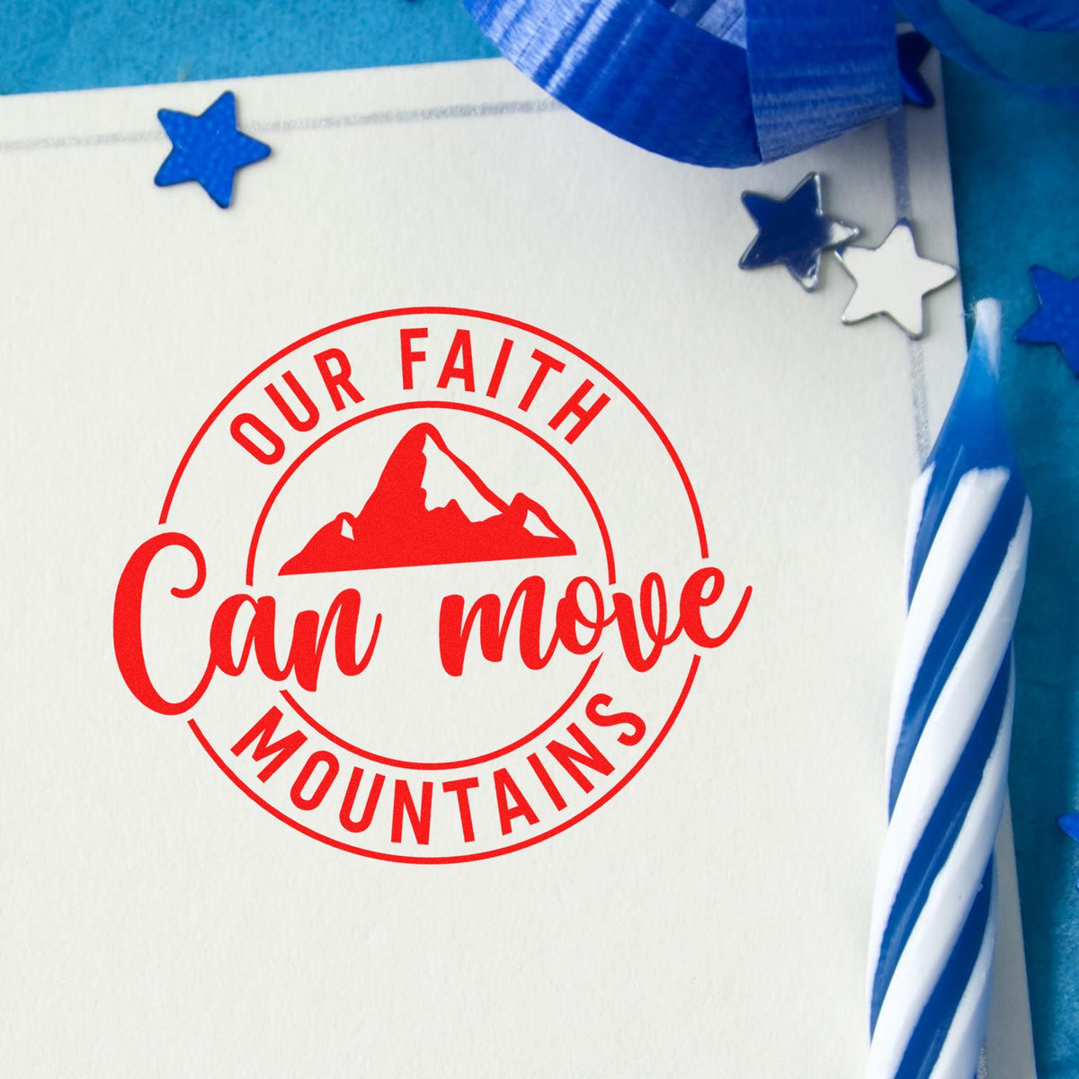 Custom rubber stamp with Our Faith Can Move Mountains in red on paper, featuring a mountain icon and blue star accents.