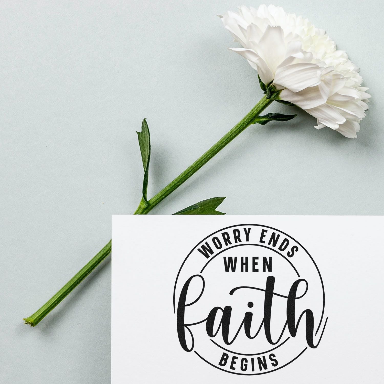 Faith-inspired rubber stamp design reading Worry Ends When Faith Begins with white flower on a soft background.