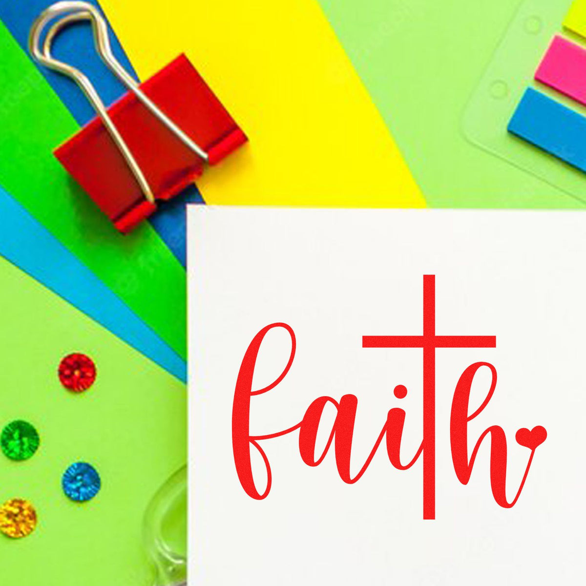 Faith rubber stamp design in red script with cross icon on white card, styled with colorful office supplies.