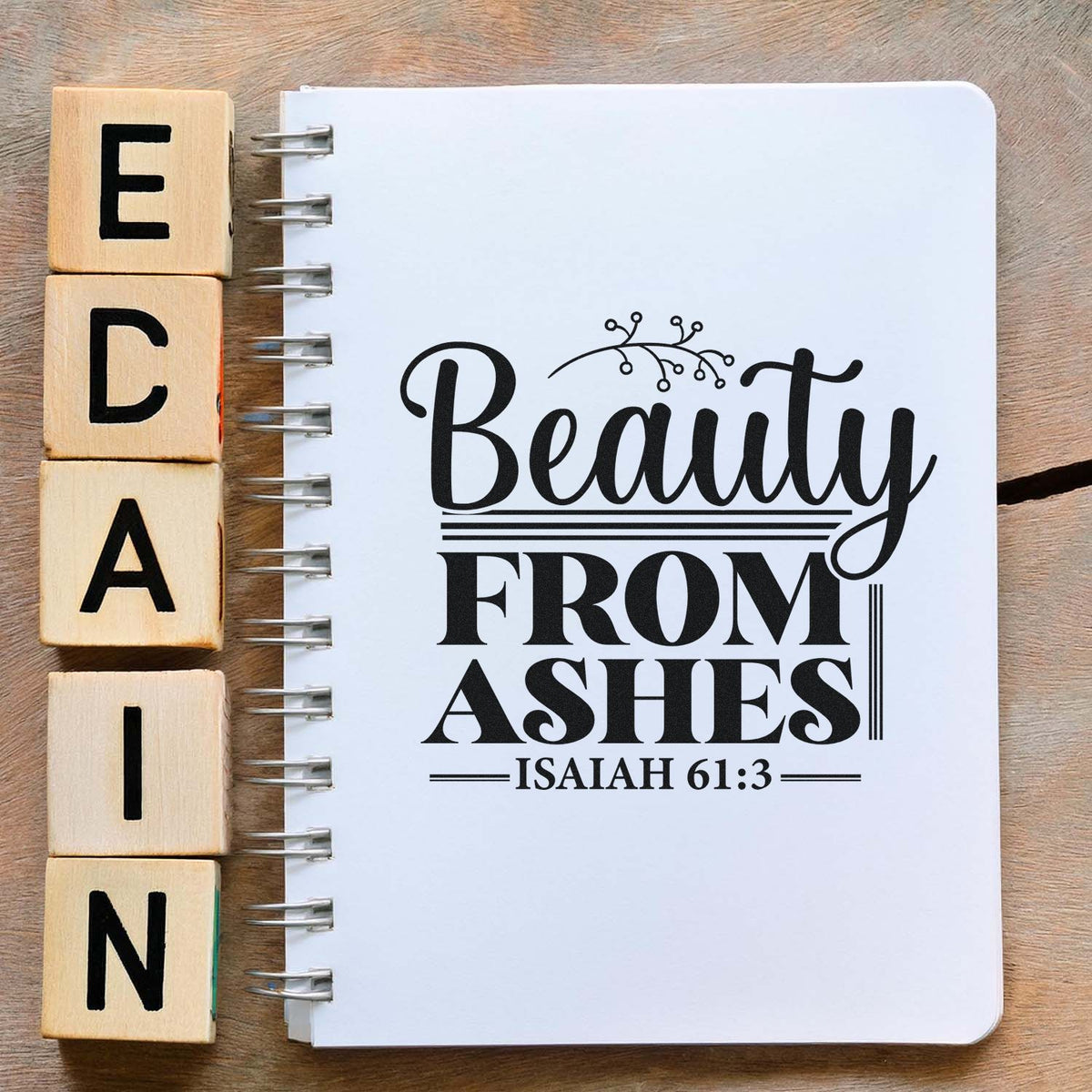 Beauty From Ashes Isaiah 61:3 rubber stamp design on notebook with wooden alphabet blocks, ideal for faith-based crafts and journaling