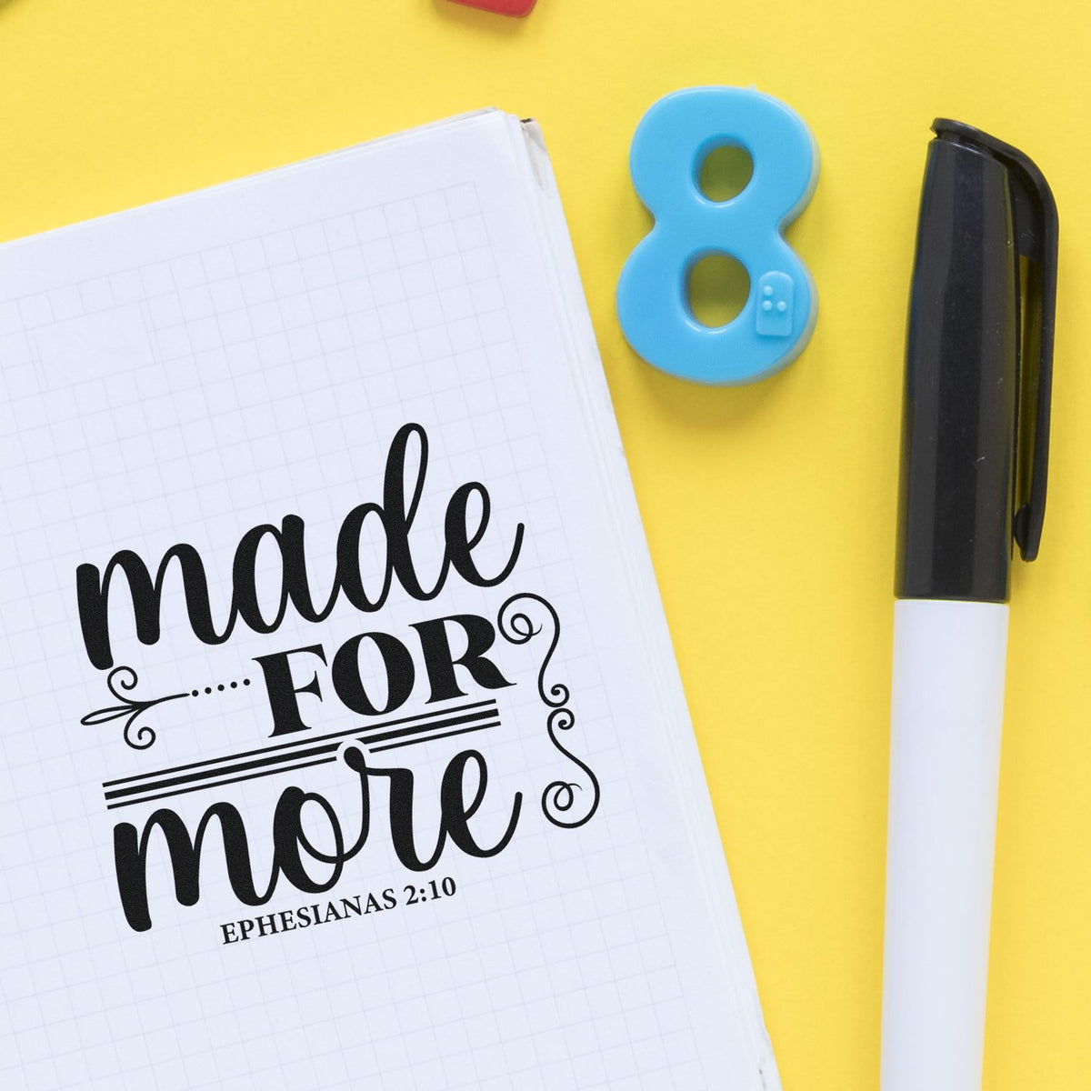 Bible verse rubber stamp design with made for more Ephesians 2:10 notebook, blue number 8 stamp, and marker on yellow background.