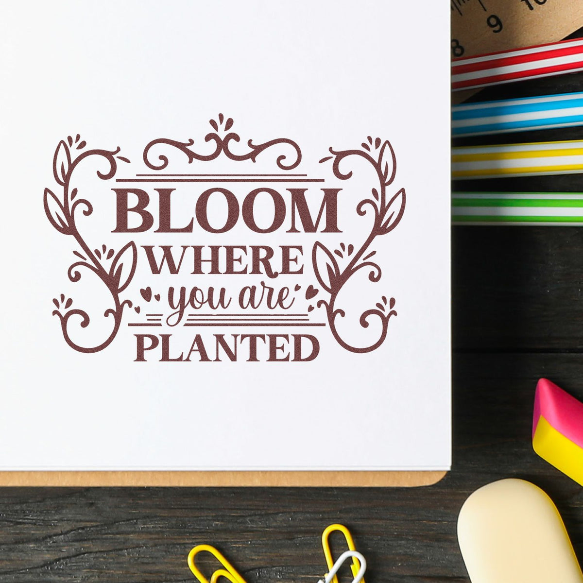 Ornamental rubber stamp with Bloom Where You Are Planted on a notebook page, ideal for inspirational journaling.