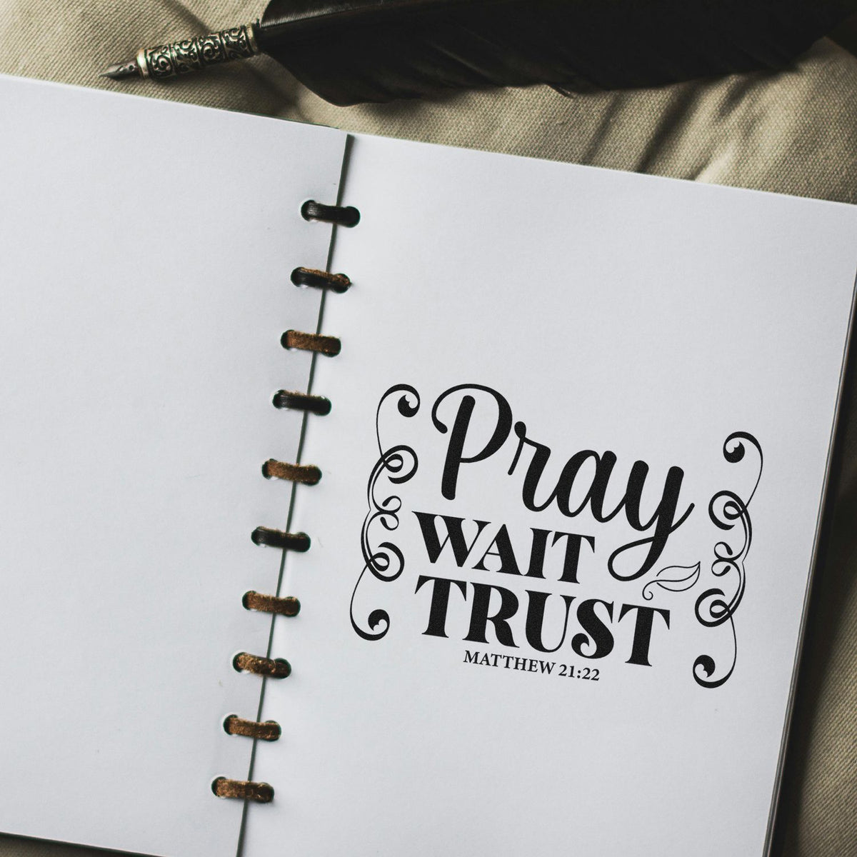 Custom faith rubber stamp reading Pray Wait Trust with Matthew 21:22 on an open journal page.