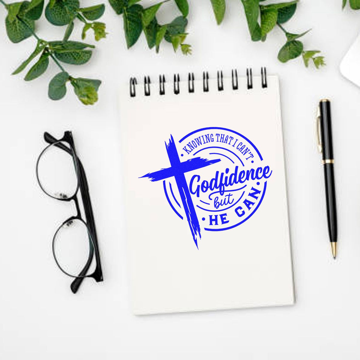 Christian rubber stamp design with blue cross and Godfidence But He Can message on notebook mockup