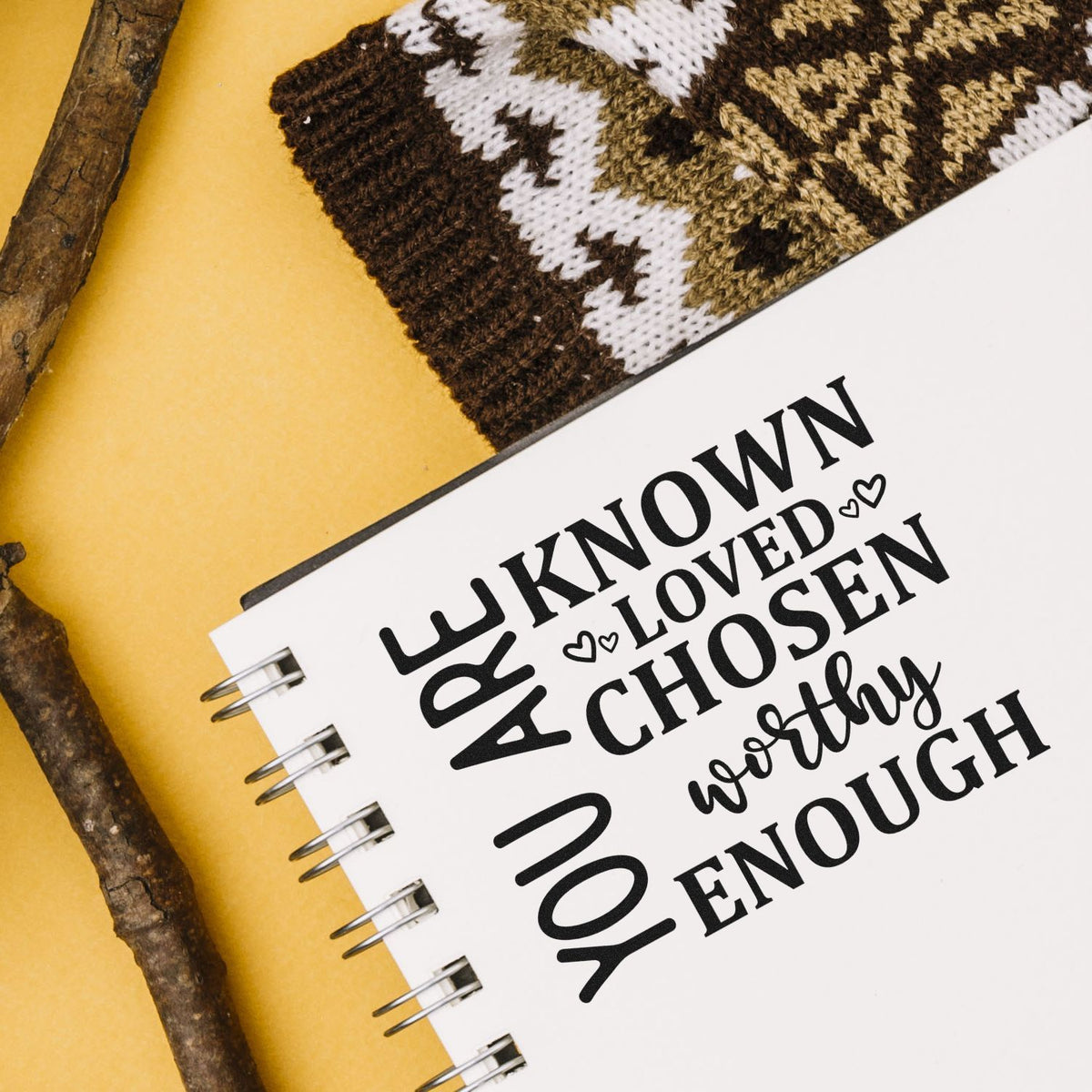 Rubber stamp design with motivational quote Known, Loved, Chosen, Worthy, Enough on a notebook.