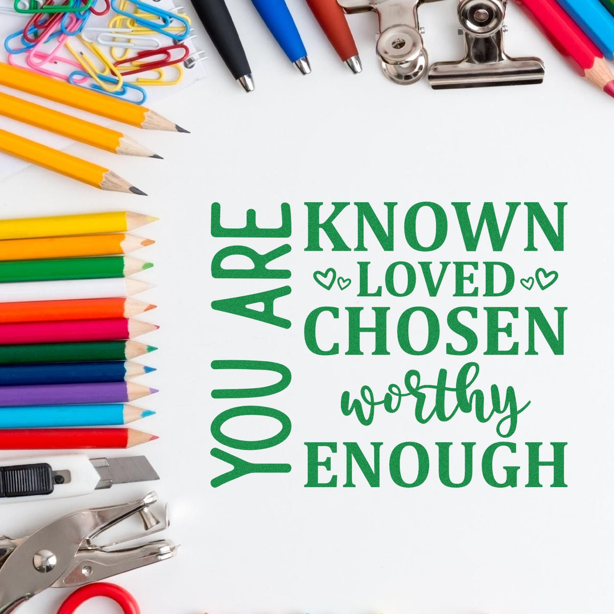 Custom inspirational rubber stamp design reading You Are Known, Loved, Chosen, Worthy, Enough, framed by pencils and office supplies.